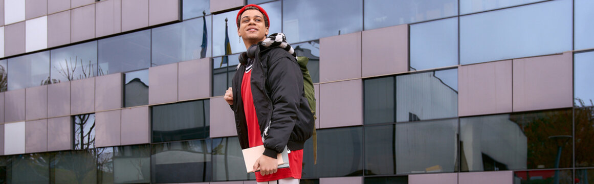 Stylish young man confidently walks through the city as he enjoys his day as a student