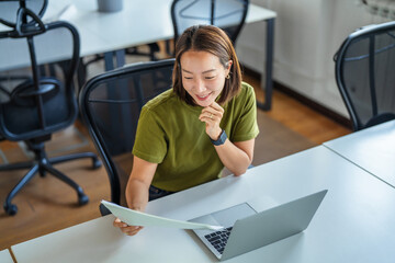 Smiling asian woman working on laptop and checking document © Miljan Živković
