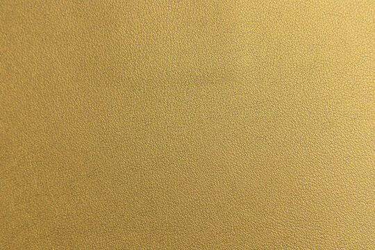 Luxury gold leather texture background. Elegant metallic leather surface with fine grain pattern. Shimmering golden