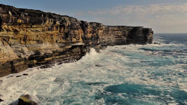 Aerial view of the rugged sandstone cliffs at Kurnell with crashing waves and turquoise water along the coastline of Sydney, New South Wales, Australia.