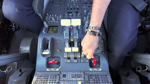 Hand of a veteran caucasian pilot (Captain seat) adjusting the thrust levers and speed brakes in a modern jet cockpit in a real time flight.