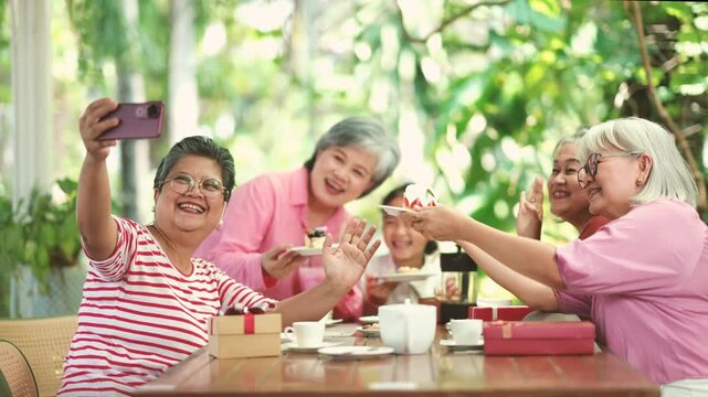 Active senior friends capturing joyful moments with smartphone through selfies and video recording while spending quality time together during retirement and social gathering