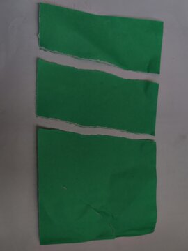 Torn green paper pieces on gray surface LK