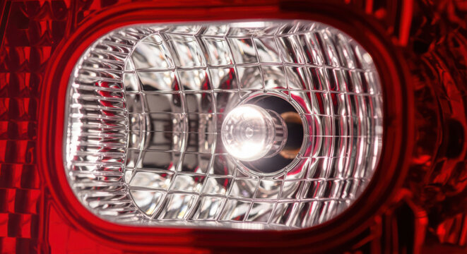 Close-up detail of a bright, illuminated car reverse light bulb within a modern automotive taillight assembly on white background. on white background