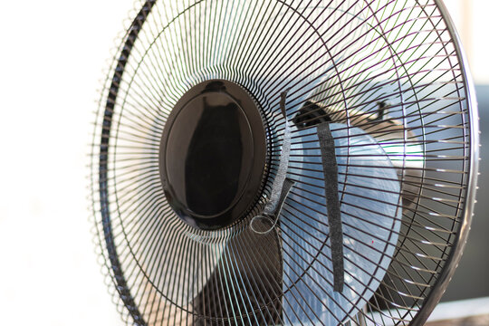 Fan spins in a room as the air circulates over surfaces and creates movement during a warm afternoon in summer