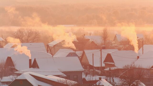 Winter village scene with smoke plumes rising from chimneys, snow-covered rooftops bathed in golden light of frosty morning sunrise.