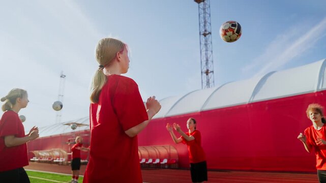 Young girls practicing soccer together on sunny training field, passing balls and developing teamwork skills during energetic youth football practice session