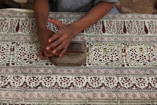 View of a craftsman using a traditional wooden block to print intricate floral patterns onto fabric in Hala, Sindh, Pakistan.