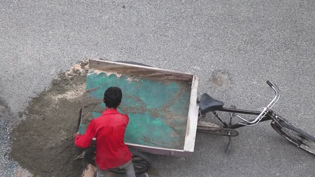 man emptying his cart of sand for building house purpose.
