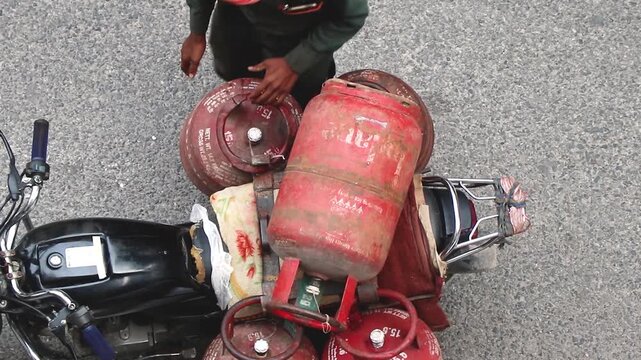 LPG gas cylinder getting transported in a motor cycle for distribution.