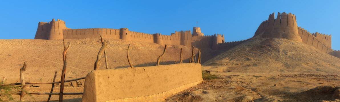 View of the historic Kot Diji Fort with its massive mud-brick walls and towers standing atop a desert hill under a clear blue sky in Kot Diji, Sindh, Pakistan.