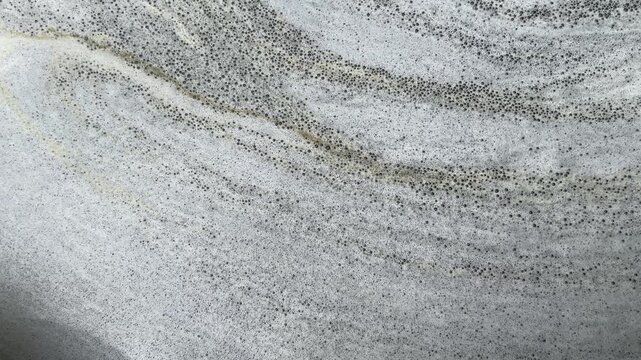Natural foamy, marble-like patterns move slowly on the water's surface; an abstract natural background.