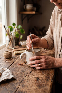 Persona che ripara una tazza in un ambiente domestico creativo. Un gesto sostenibile che rappresenta riuso, artigianalit&agrave;, eco lifestyle e filosofia zero waste.