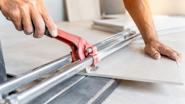 Contractor cutting ceramic tile with a manual cutter in home renovation project