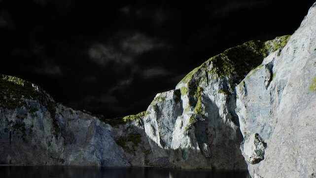Tall rocky cliffs surround a still body of water. The dark sky has thick clouds, creating a dramatic atmosphere. The scene shows the natural beauty of the landscape.