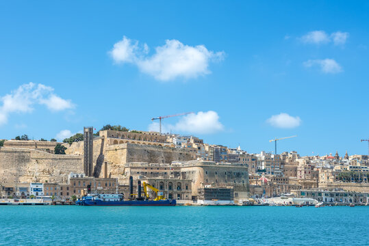 Panoramic view of the historic Valletta Bastions and Barrakka Lift above the Grand Harbour with limestone fortifications, waterfront and blue Mediterranean sea