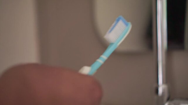 Hand applying toothpaste to a toothbrush before brushing teeth. Healthy lifestyle and oral care routine captured in detailed close-up.