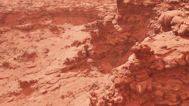 The setting shows a rocky terrain with various formations in shades of red. The sunlight highlights the details of the rocks, creating shadows and depth in the scene.