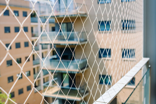 A safety net is installed on a balcony to prevent falls in a high-rise residential building in an urban setting