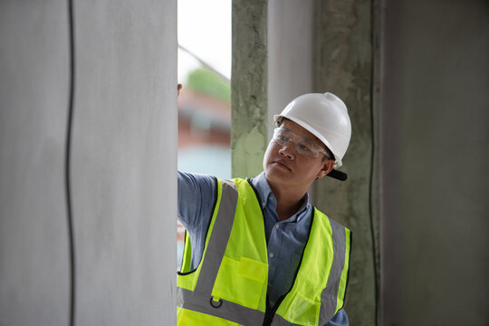 Construction worker inspecting structural elements at a building site with safety gear and equipment