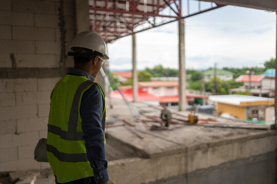 Construction site engineer wearing safety gear while examining machinery and the surrounding area for quality assurance