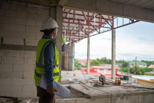 Construction professional monitoring project development while wearing safety equipment in an industrial environment