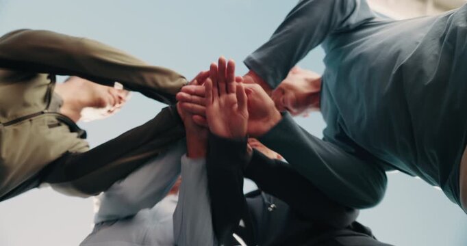 People, friends and hands together for fitness, exercise or outdoor mission below blue sky. Low angle, active group or piling with stack, synergy or community in huddle for wellness or teamwork