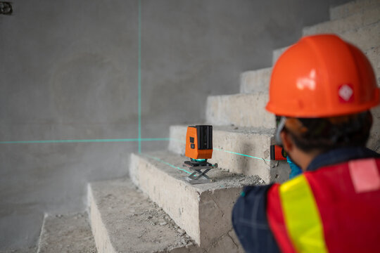 Construction professional utilizing a laser level to ensure precise measurements on staircases at a building site