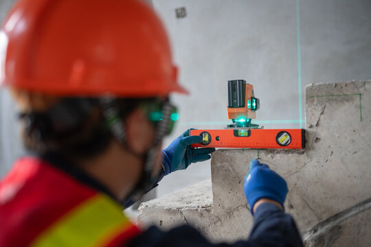Construction professional utilizing a laser level for precise measurements at a job site