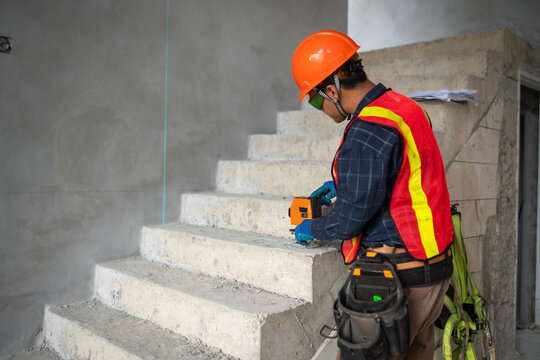 Construction professional using laser measurement tool to assess the quality of concrete stairs at the building site
