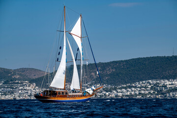 Fototapeta premium Luxury wooden sailing yacht cruising on the deep blue sea water, elegant classic sailboat navigating during a scenic summer vacation cruise travel, premium Mediterranean maritime lifestyle concept