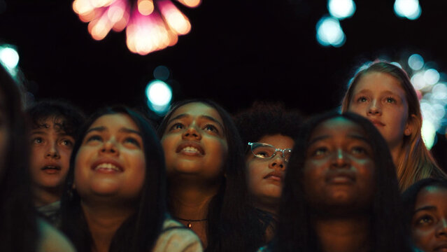 Diverse American children of different ethnicities looking up at fireworks with pure wonder and awe on their faces