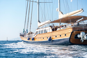 Obraz premium Luxury wooden sailing yacht cruising on the deep blue sea water, elegant classic sailboat navigating during a scenic summer vacation cruise travel, premium Mediterranean maritime lifestyle concept