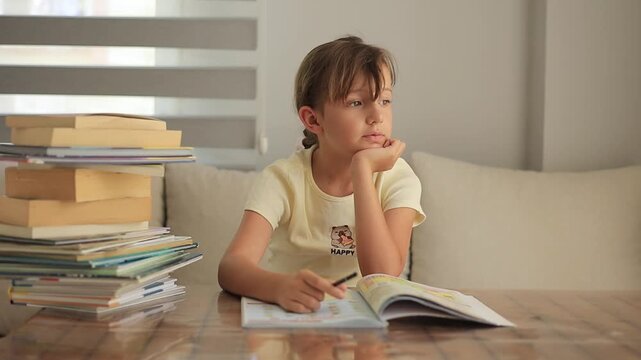 Young girl studying at home with a stack of books