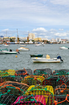 View of colorful fishing traps in the foreground with boats and cranes in the harbour of Algarvia, Azores, Portugal.