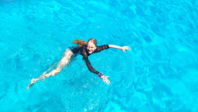 Young happy girl swimming in the crystal clear turquoise waters of the Mediterranean Sea near Protaras, Cyprus. Summer vacation, family travel, healthy lifestyle, freedom and joyful outdoor recreation