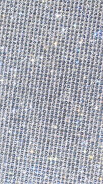 Sparkling rhinestone mesh texture. Close-up of densely packed silver crystals and sequins with twinkling highlights, slow camera movement over luxurious reflective surface. 