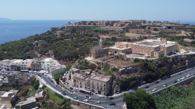 Drone view of Mgarr harbour in Gozo Island, Malta. Church of the Madonna of Lourdes on the right and Fort Chambray on top of the hill. High quality 4k footage