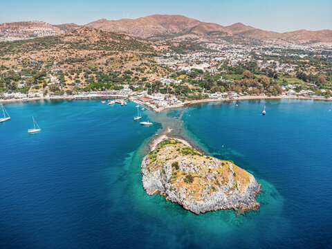 Aerial view showing Rabbit Island and the charming village of Gumusluk, Bodrum with boats in blue Aegean waters in Turkiye
