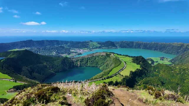 Cinematic panoramic view from Grota do Inferno on Sao Miguel Island Azores Portugal showcasing the iconic Sete Cidades crater lakes lush volcanic caldera and Atlantic Ocean horizon