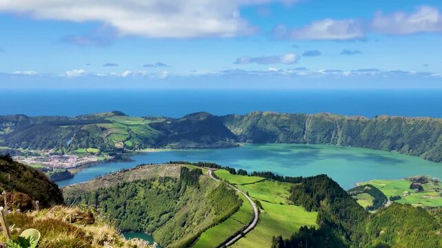 Cinematic panning view across Sete Cidades on Sao Miguel Island Azores Portugal showcasing the emerald crater lake lush volcanic caldera rolling green hills and the Atlantic Ocean