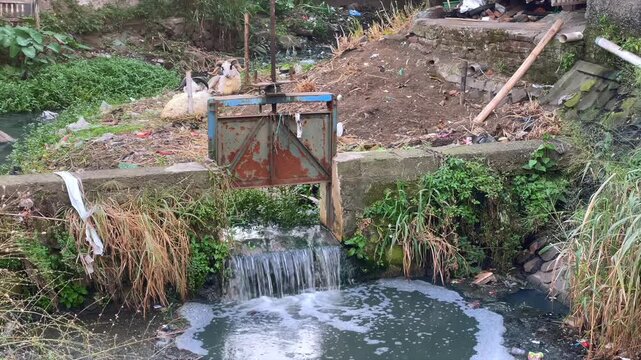 Water flowing through a rustic metal irrigation gate in the countryside