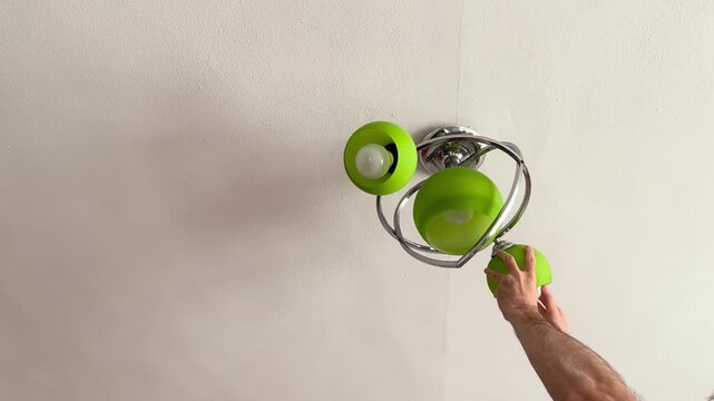 Home maintenance worker replacing ceiling light bulb