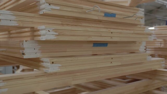 Stack of unfinished wood window frames stored in a manufacturing factory, showcasing organized timber components ready for assembly or finishing