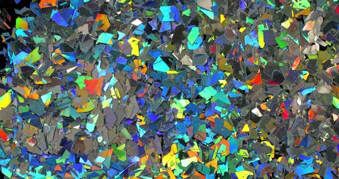 Iridescent holographic flakes slow rotation. Close-up of dense multicolored shiny fragments with vibrant blue, cyan, orange and gold reflections.