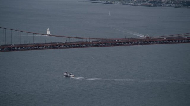 Golden Gate Bridge With Motorboat And Sailboat Passing Below - Aerial Shot