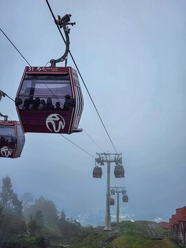 Genting Highlands, Malaysia - January 10, 2026: A cable car gondola branded with Coach insignia carries passengers through thick fog above the Genting Highlands mountain resort.
