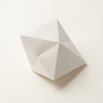 Paper texture geometric shape white origami polyhedron with sharp folds and cream background