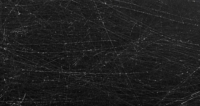 Dark scratched texture. Close-up view of a matte black surface with dense fine scratches and subtle wear marks. Smooth continuous rotation reveals evolving light reflections.
