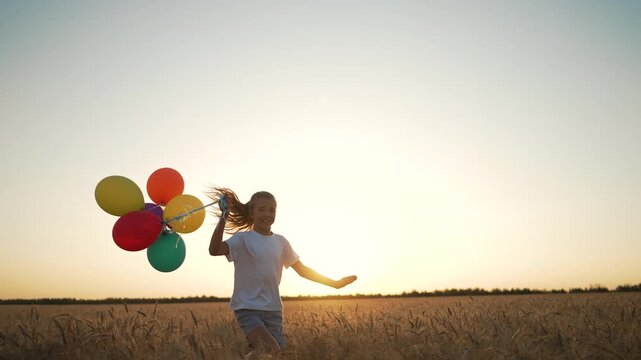 Child with balloon in wheat field at sunset. Happy child running through wheat holding balloon. Wheat field glowing at sunset with child and balloon. Joyful moment for child with balloon wheat field.